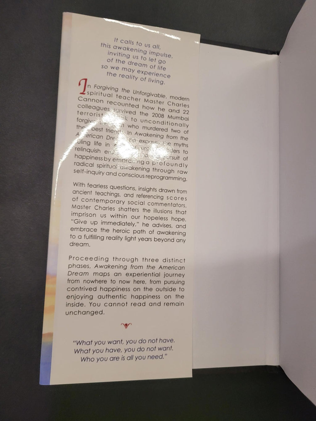 A printed booklet or card with dense black text and a red decorative letter, photographed inside an open white box on a dark surface.
