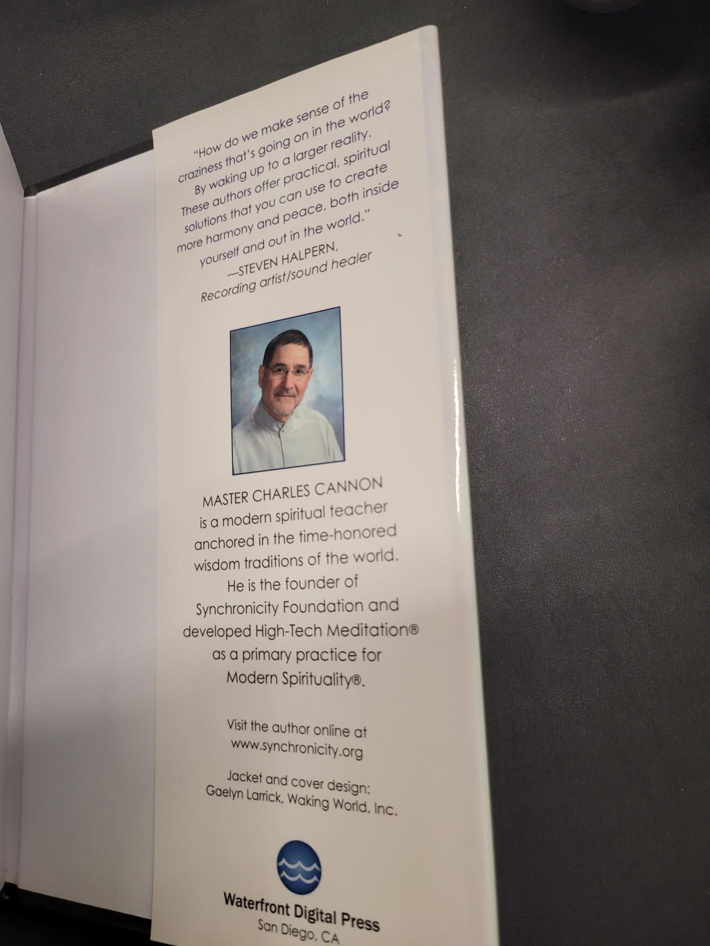 A printed booklet or card with text, a small portrait photo of a man, and a visible 'Weathered Digital Press' logo, photographed on a dark gray surface.