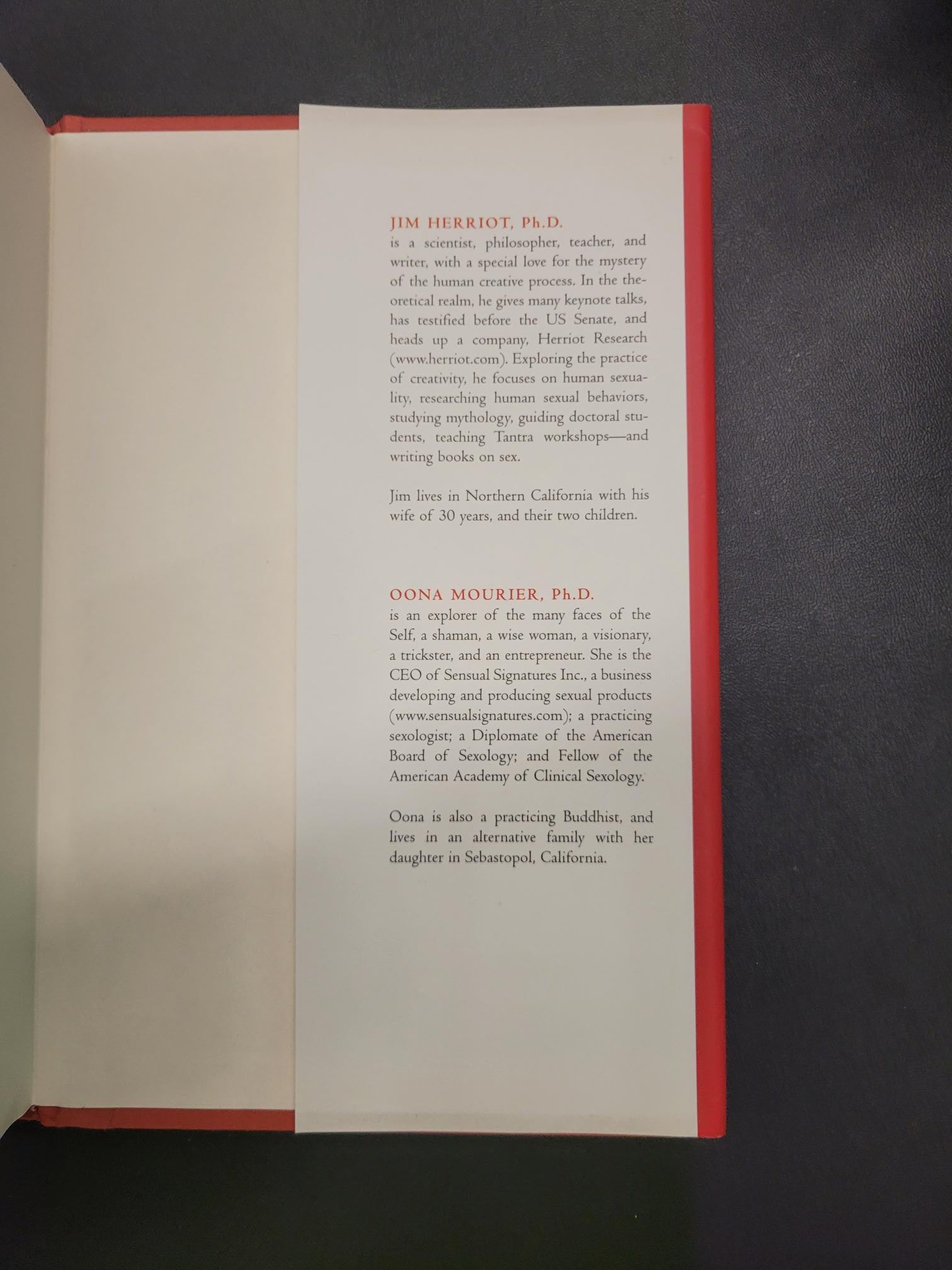 An open book or booklet showing printed text on a white page with a red top border, photographed from above on a dark gray surface.
