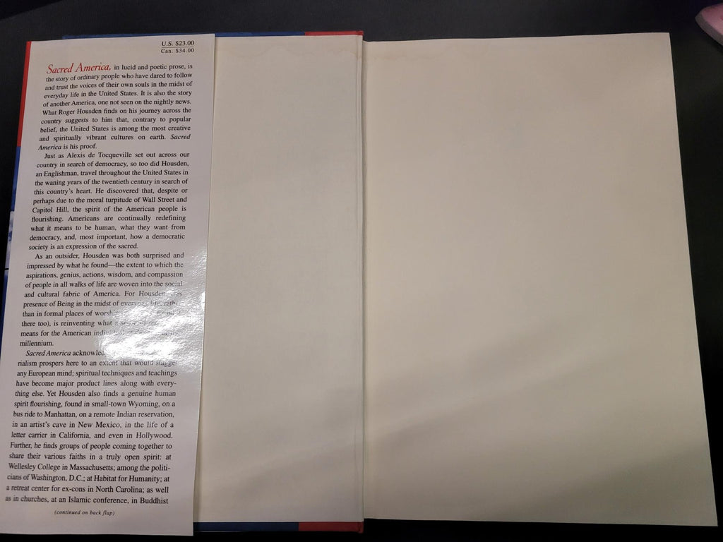 An open book or booklet showing a blank cream-colored page on the lower half and printed text on the upper half, photographed from above on a dark surface.