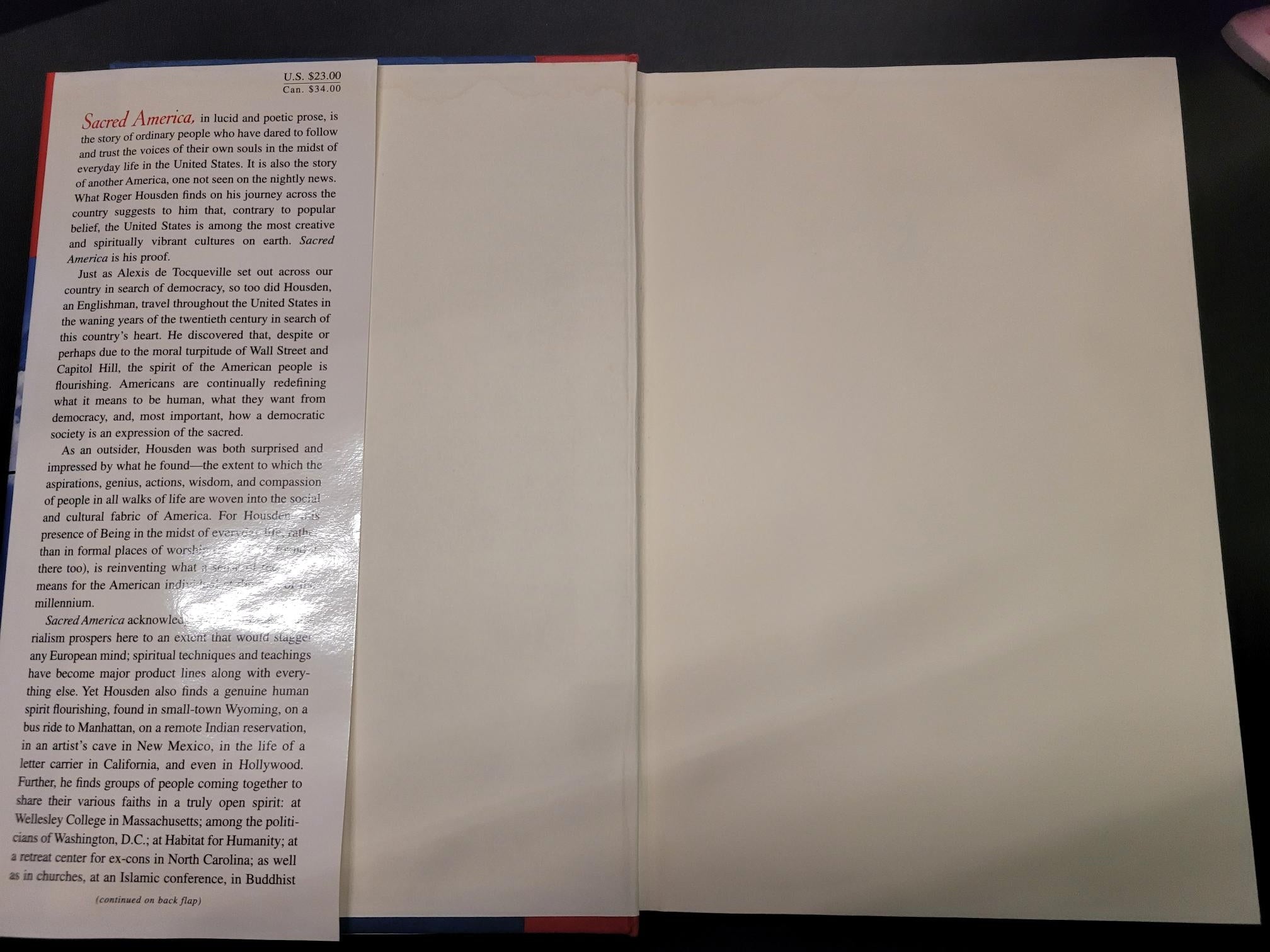 An open book or booklet showing a blank cream-colored page on the lower half and printed text on the upper half, photographed from above on a dark surface.