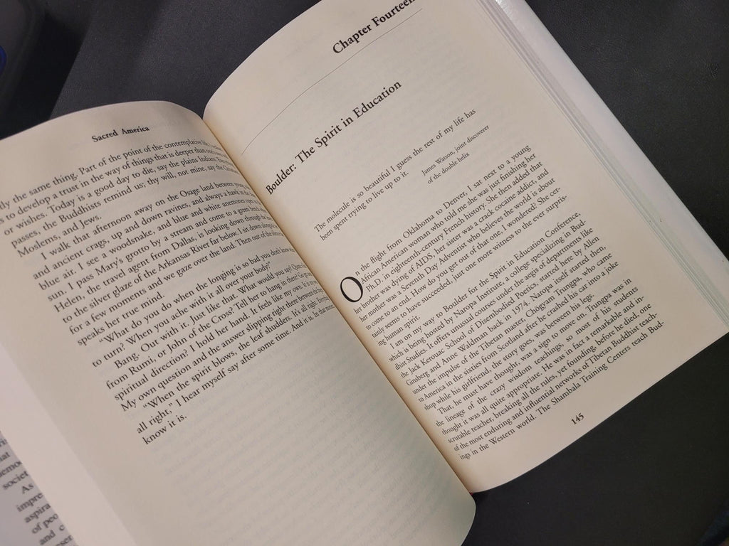 An open book showing printed text on cream-colored pages, photographed from above on a dark surface.