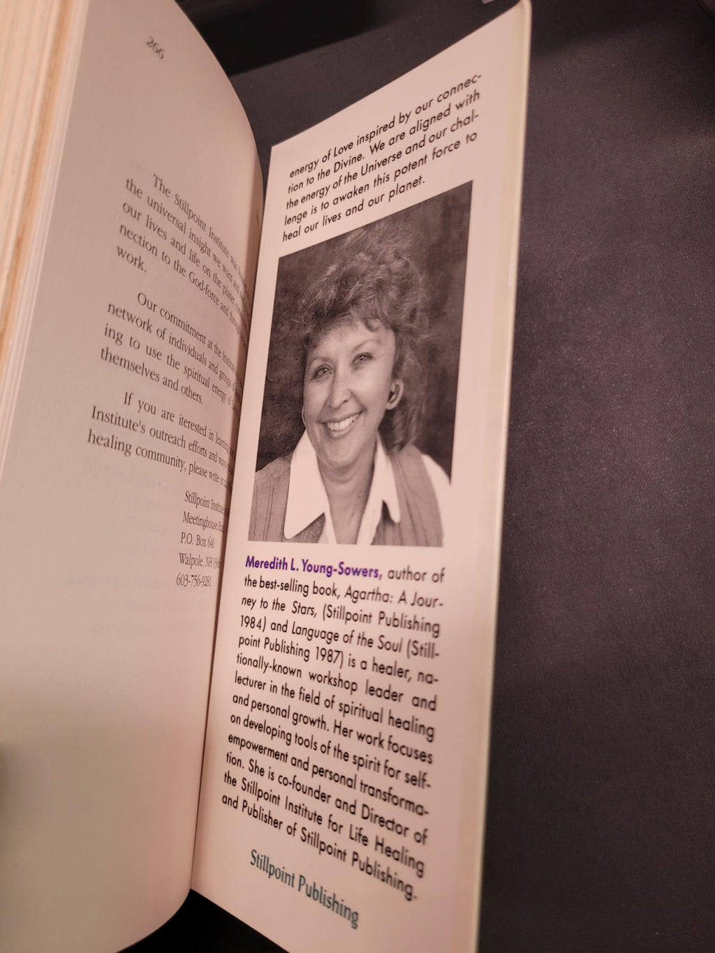An open book showing printed text and a black-and-white portrait photo on one page, photographed against a dark background.