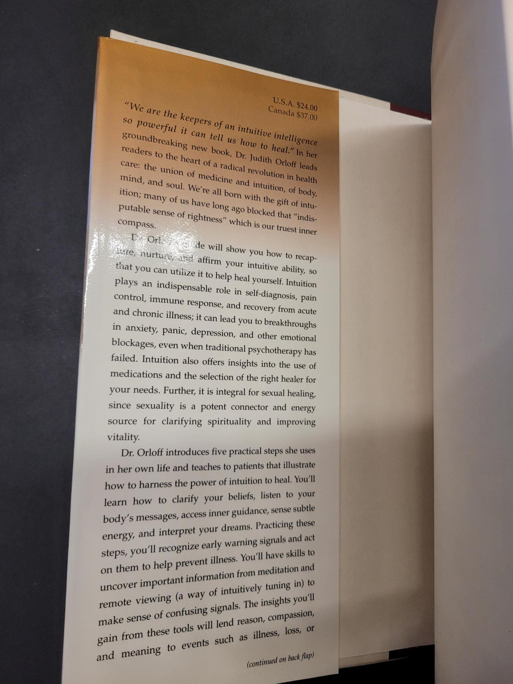 A printed page or booklet page with black text on a warm tan background, photographed from above on a dark surface.