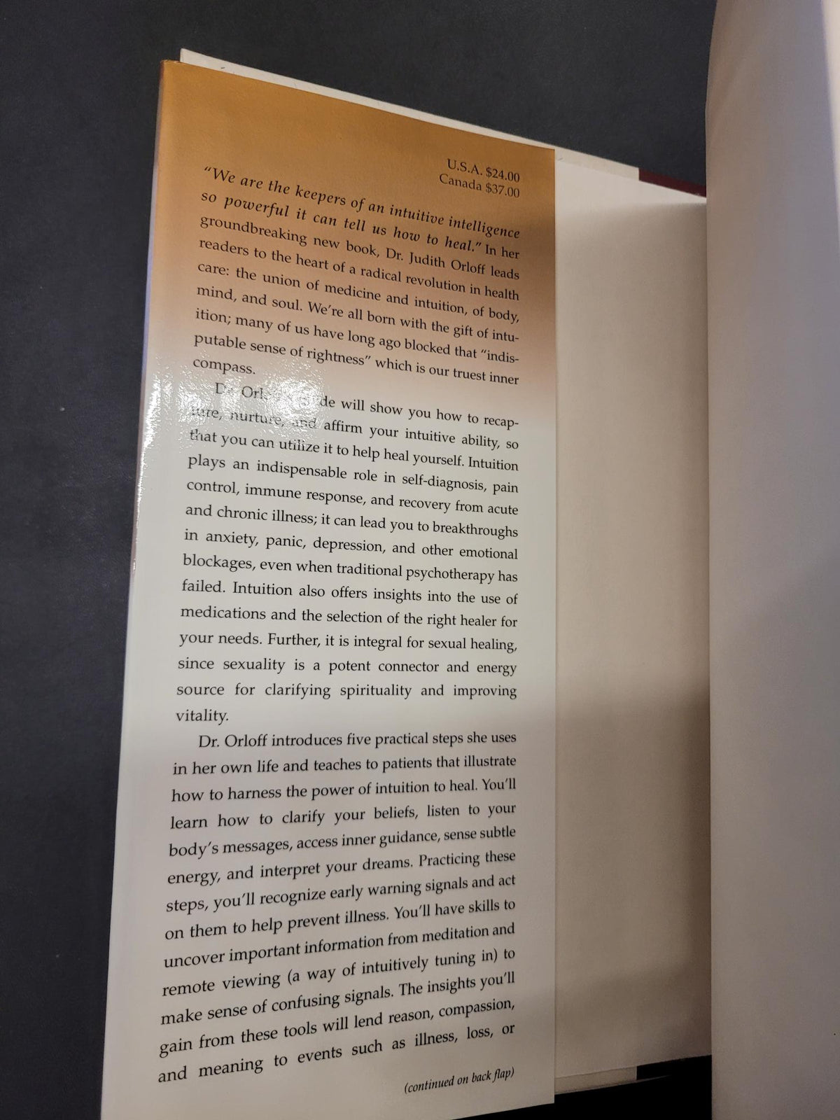 A printed page or booklet page with black text on a warm tan background, photographed from above on a dark surface.