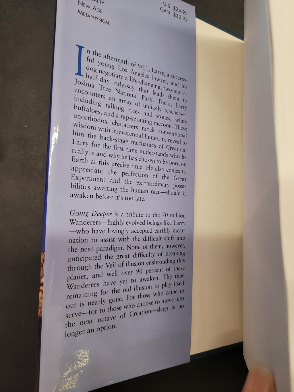 A close-up of printed text on a blue book or booklet page, photographed from above on a dark surface with part of a hand visible at the top edge.