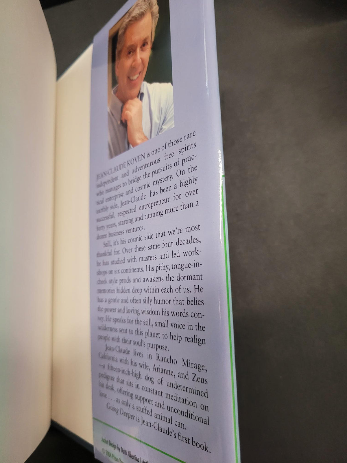 A close-up of a printed book or booklet page with a small portrait photo of a man on the left and columns of black text on a white page, photographed against a dark gray background.