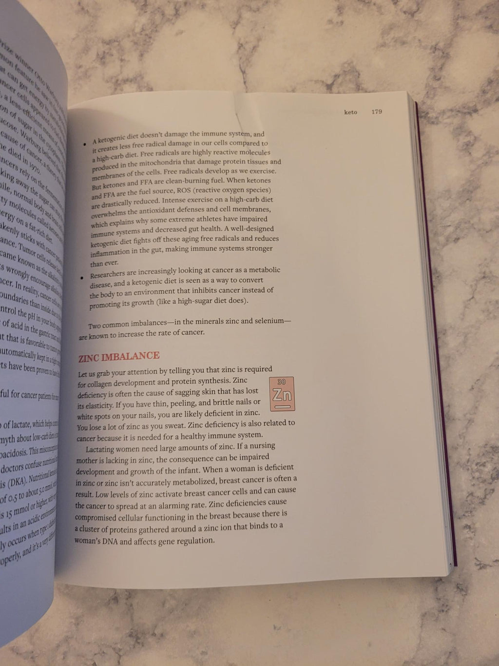 An open book showing printed text pages on a light marble surface, with the right page turned slightly to the side.