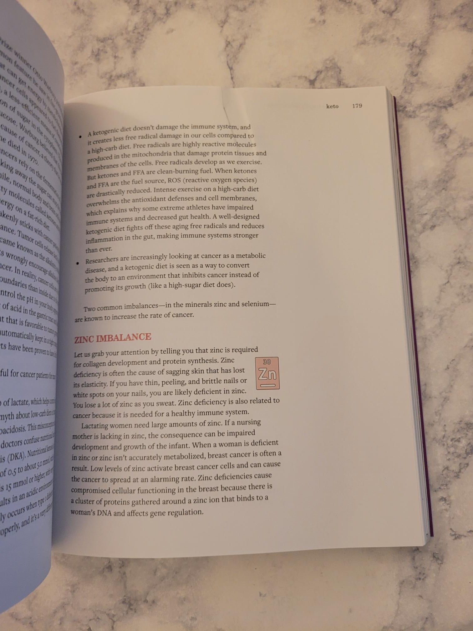 An open book showing printed text pages on a light marble surface, with the right page turned slightly to the side.
