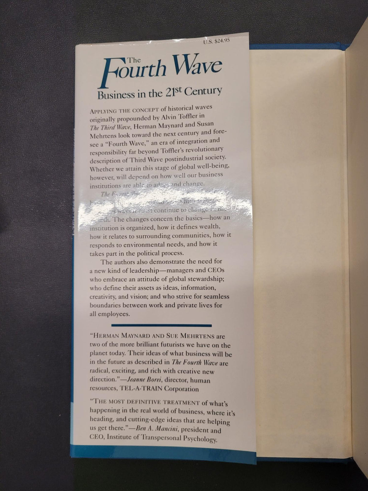 An open book or booklet lying on a dark surface, showing printed text pages with a prominent title reading 'The Fourth Wave' and a blue border along the page edges.