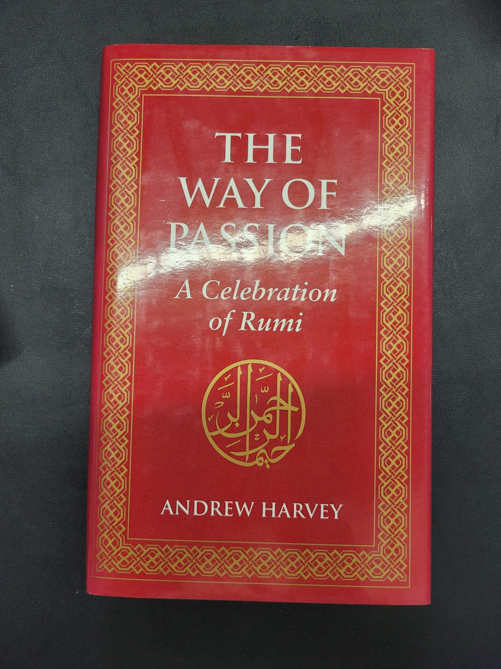 The Way of Passion: A Celebration of Rumi by Andrew Harvey, featuring a red hardcover with gold decorative borders and gold lettering, photographed on a dark background.