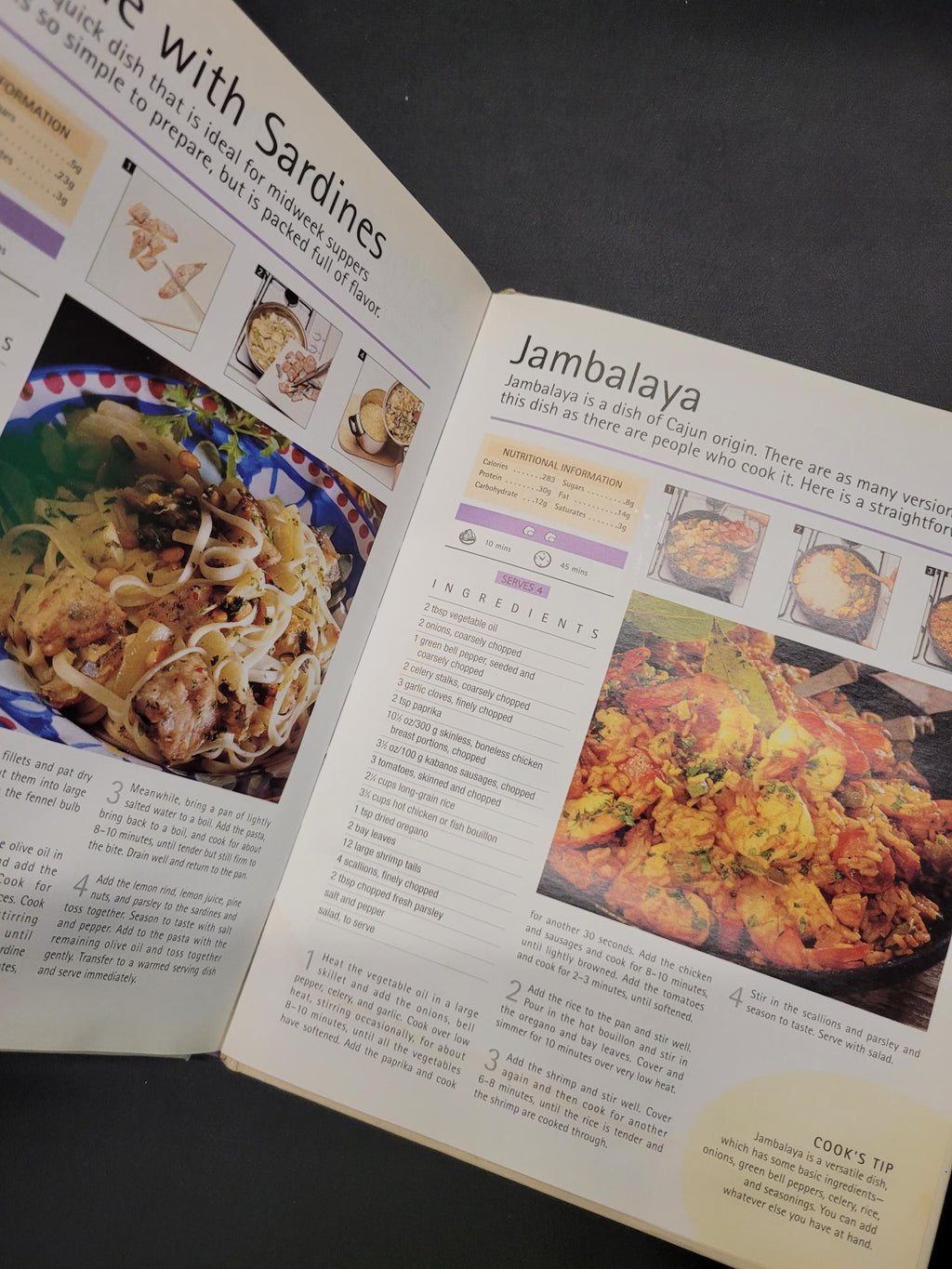 An open printed cookbook or recipe book spread on a dark surface, showing pages with food photography, ingredient lists, and recipe text. The visible page headings include Jambalaya and Sardines.