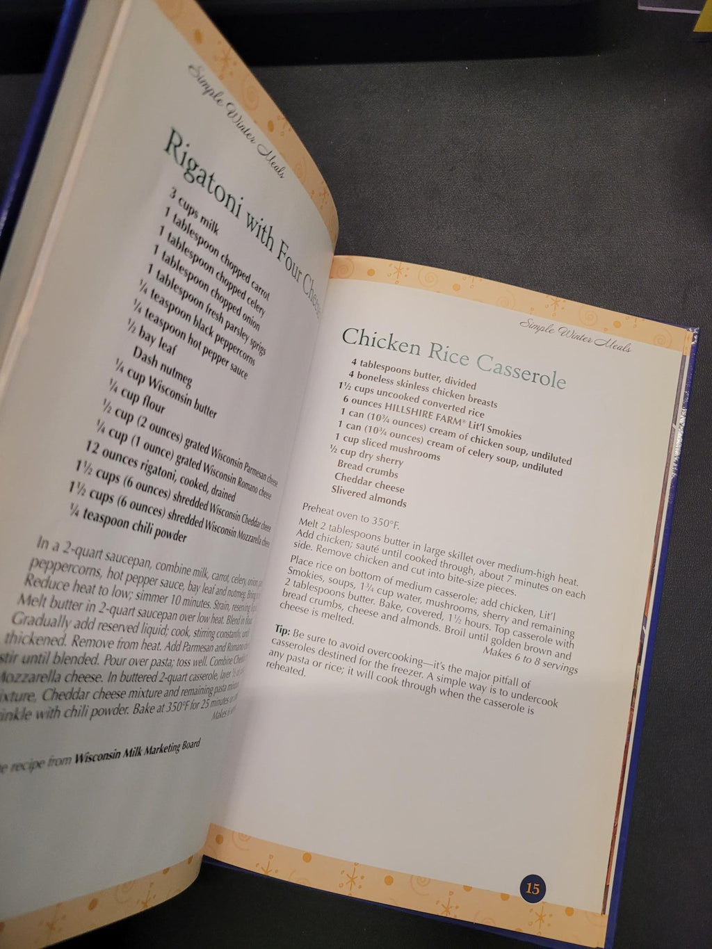 An open cookbook showing two recipe pages, including Chicken Rice Casserole and Rigatoni with Four Peas, photographed against a dark background.