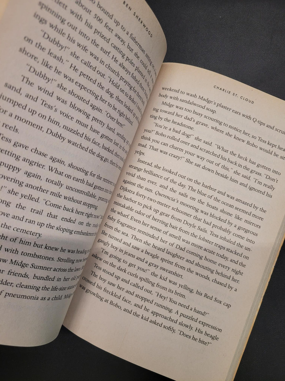 An open book with printed text spread across two pages, photographed from above against a dark background.