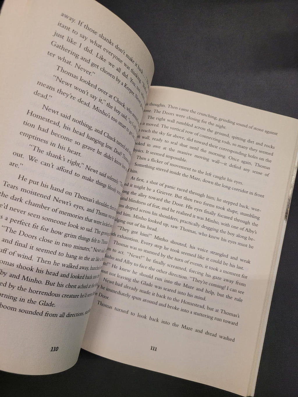 An open book showing printed text on two pages, photographed against a dark gray background.