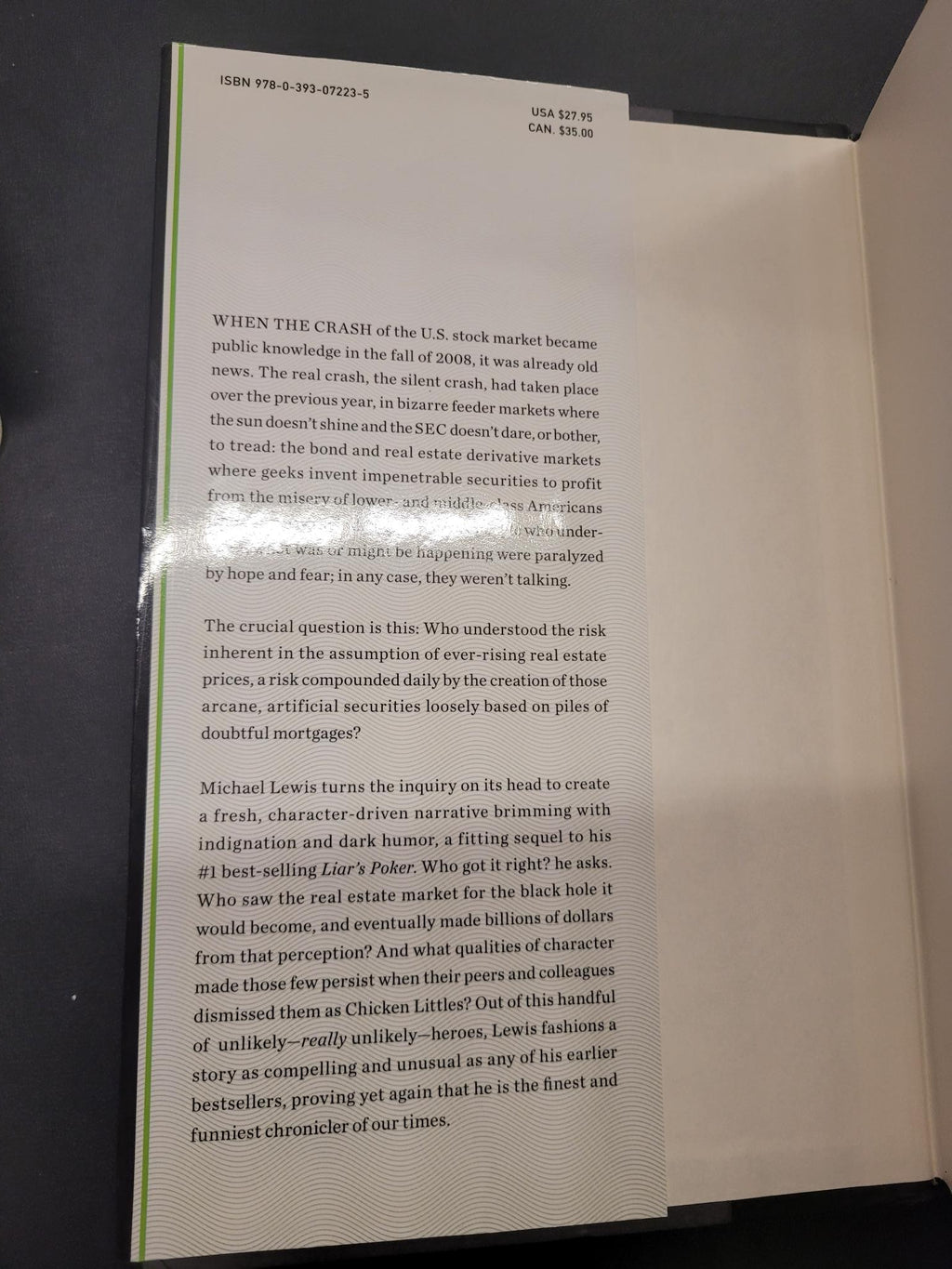 An open book or booklet showing printed text on both pages, photographed from above on a dark surface. The left page has a light beige/cream cover and the right page is white with black text.