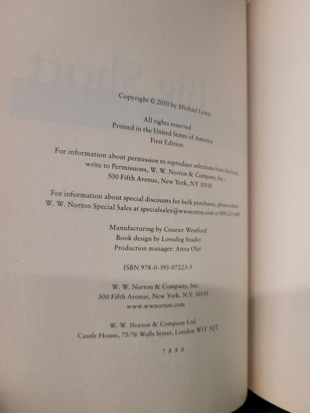 A close-up of an open book's printed copyright page, showing black text on an off-white page with a dark surface visible underneath.