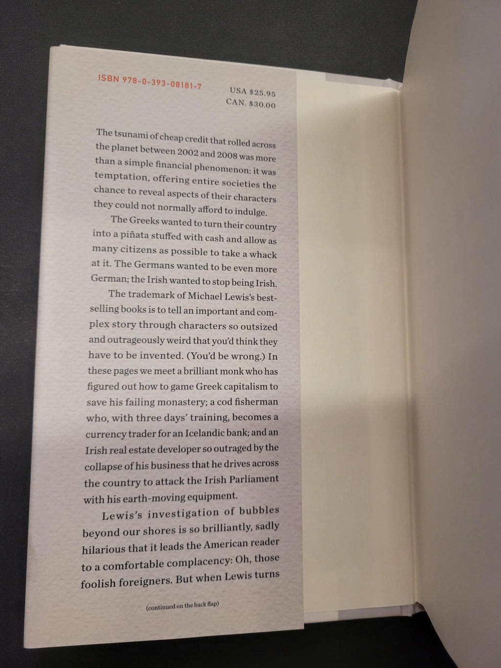 A book's interior page with printed text, photographed from above on a dark surface with the white book cover visible behind it.