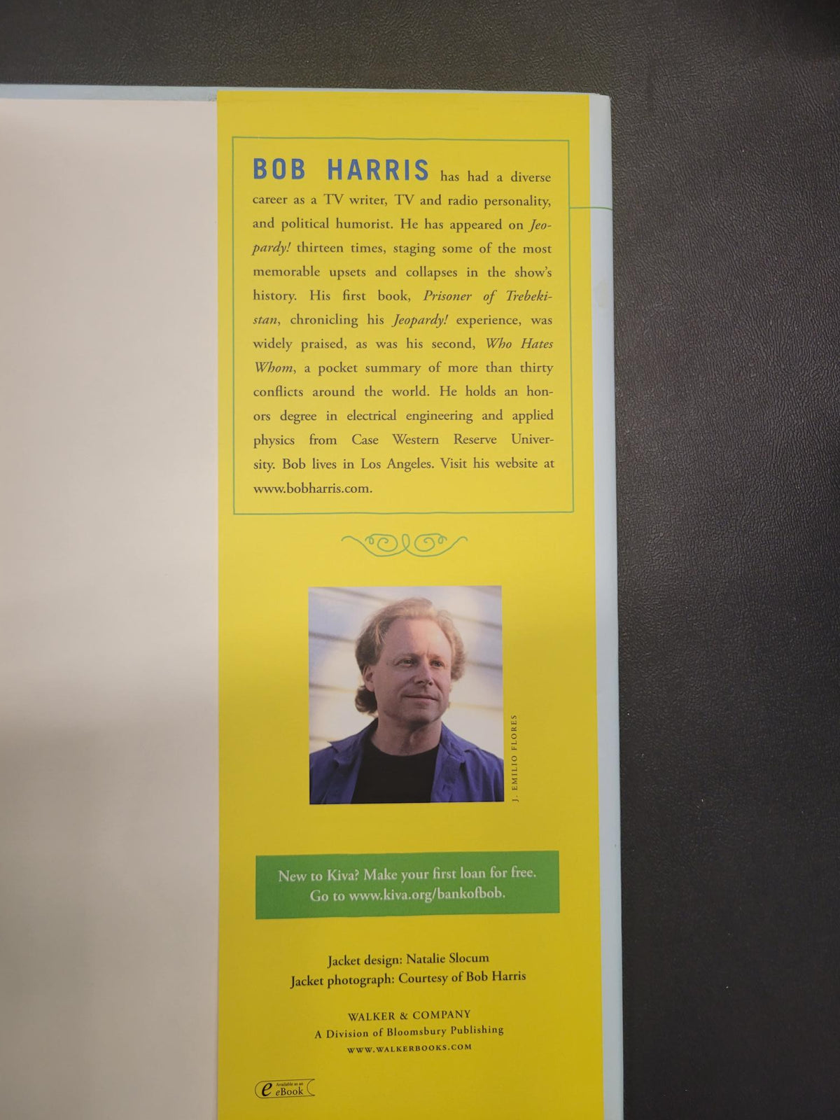 A printed book or booklet page with a large yellow vertical panel containing biographical text about Bob Harris and a small portrait photo, photographed against a dark gray surface.