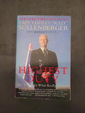 A paperback copy of the book 'Highest Duty: My Search for What Really Matters' by Capt. Chesley 'Sully' Sullenberger with Jeffrey Zaki, featuring a portrait of Sullenberger on the front cover against a dark gray background.