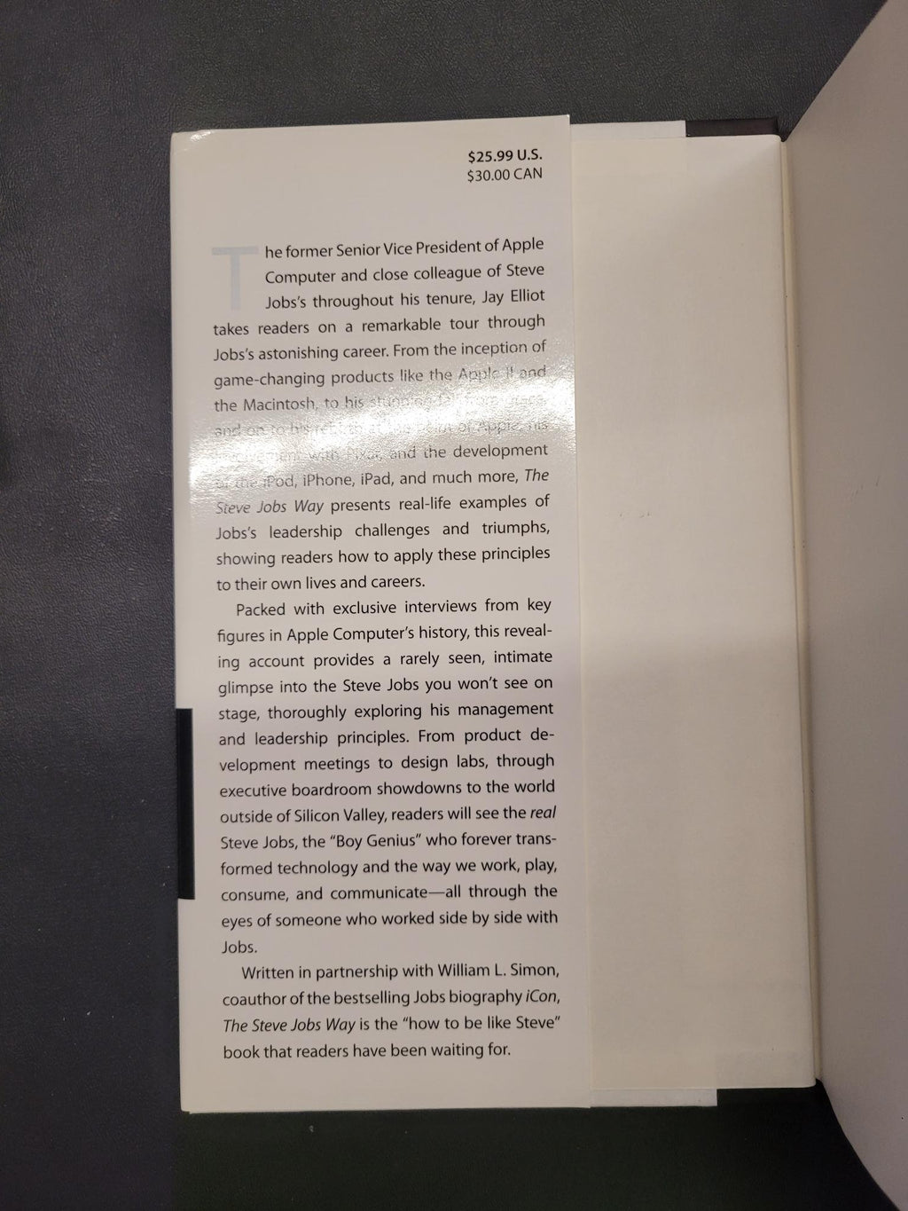 A printed white booklet or card with black text, photographed inside an open white box against a dark background.