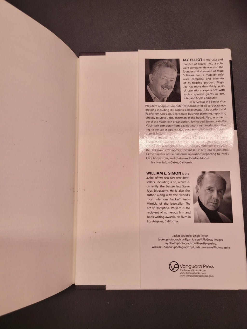 An open book or booklet showing printed pages with black-and-white portrait photos, columns of text, and a visible Vanguard Press logo on the right page, photographed against a dark background.