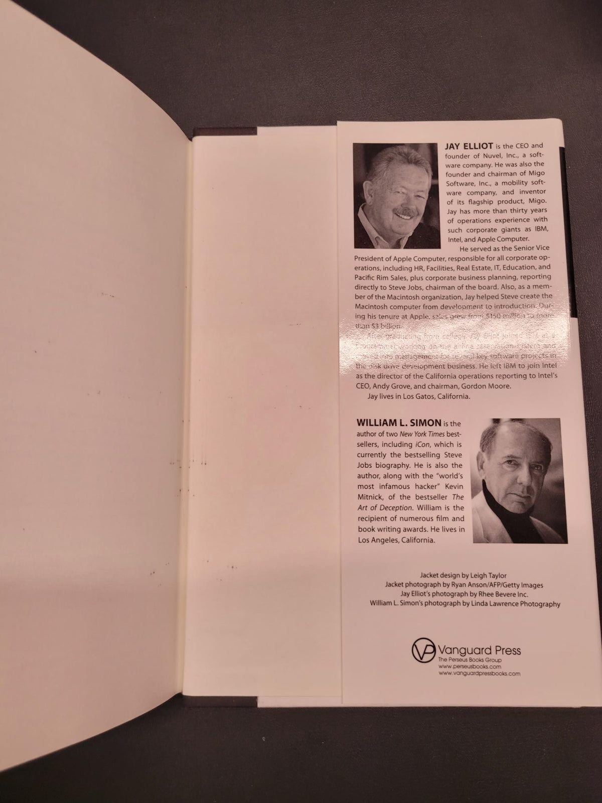 An open book or booklet showing printed pages with black-and-white portrait photos, columns of text, and a visible Vanguard Press logo on the right page, photographed against a dark background.