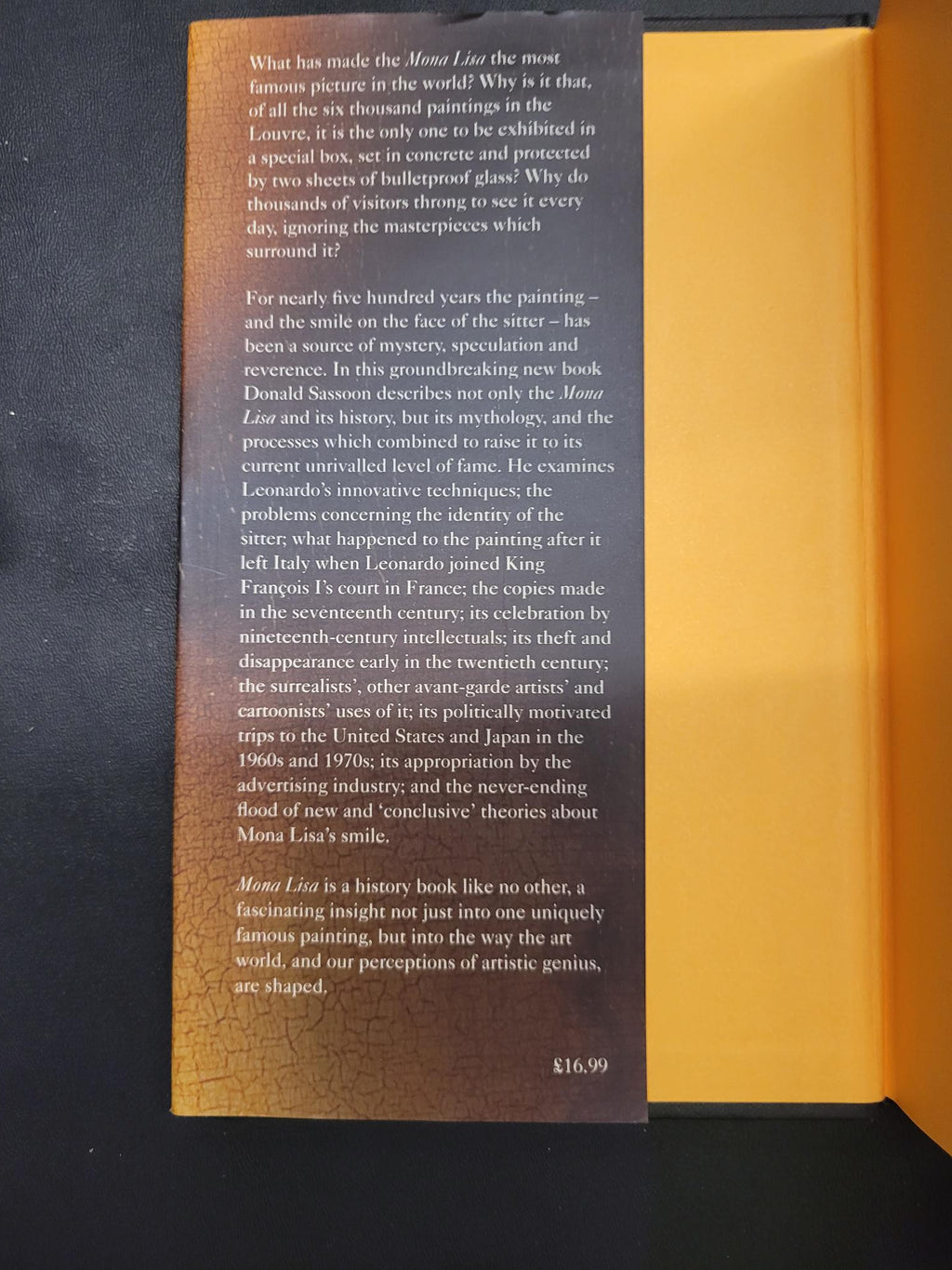 A printed card or insert with text, photographed inside an open yellow-orange book or folder on a dark surface.