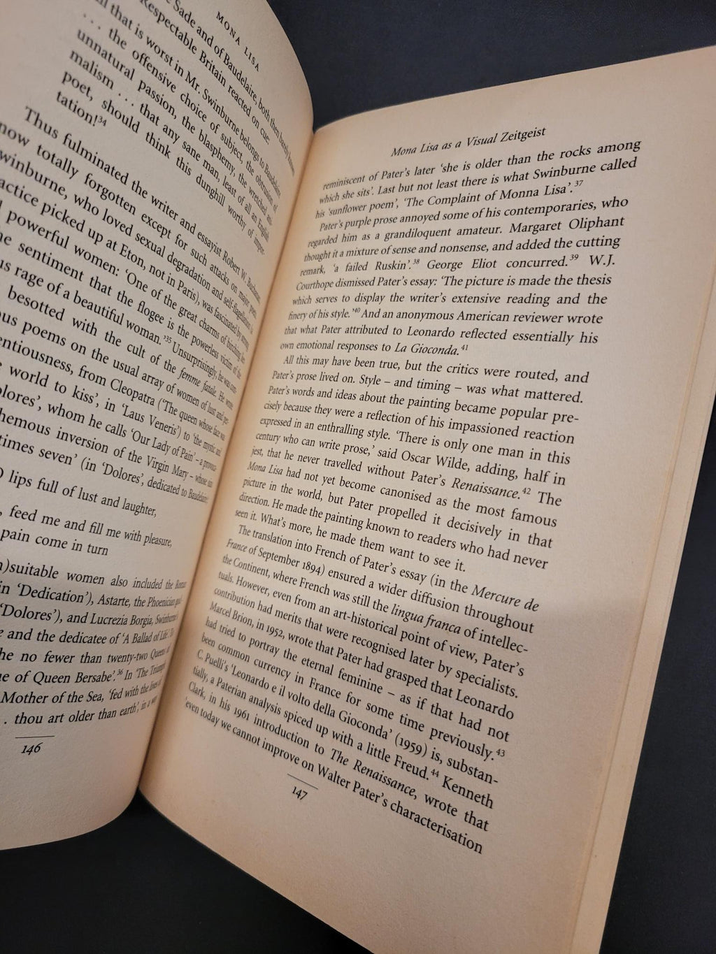 An open book with cream-colored pages displaying printed black text, photographed against a dark background.