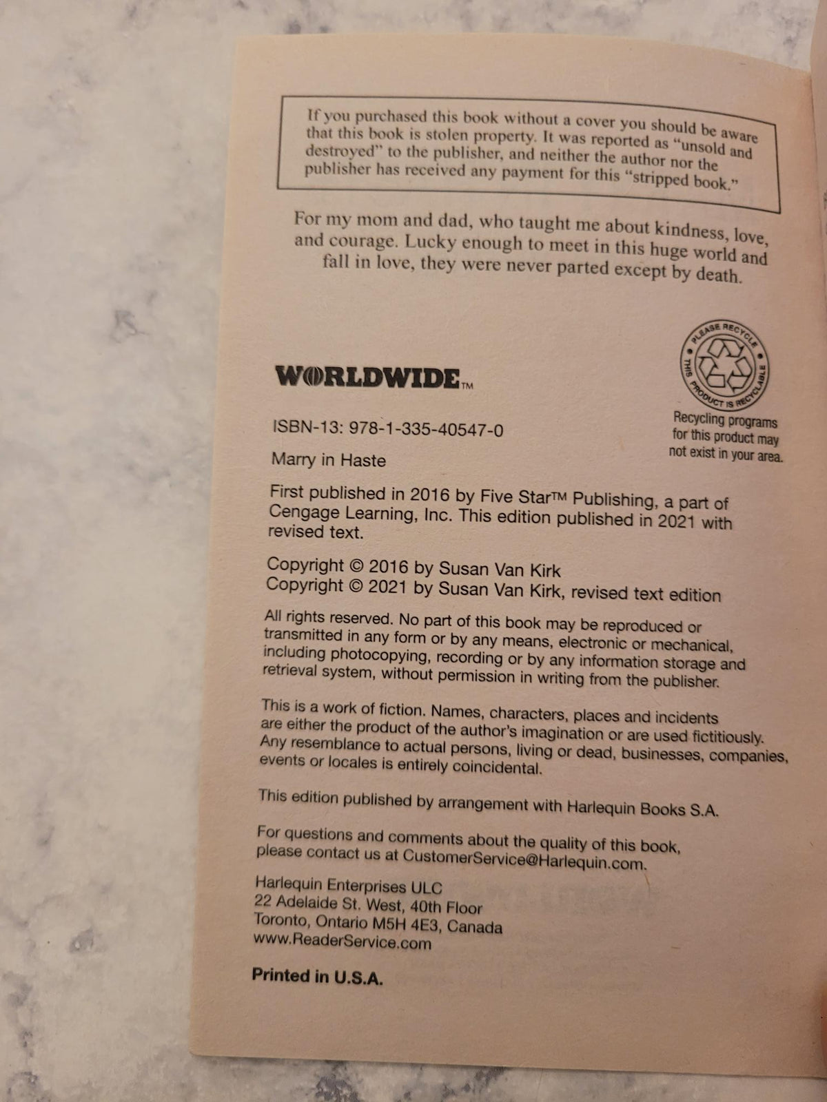 A beige paper insert or copyright page with black text and a circular logo, photographed on a light marble-like surface.