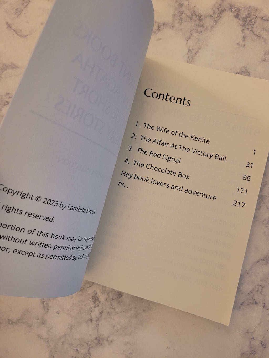 An open book showing the table of contents page, photographed on a light marble surface.