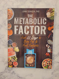 The book cover of 'The Metabolic Factor' by Jonny Bowden, PhD, displayed flat on a light gray marble surface. The cover features a dark wood background with various food illustrations around the edges and a blue 'Also Inside' 10 Meal Plan booklet shown at the bottom.