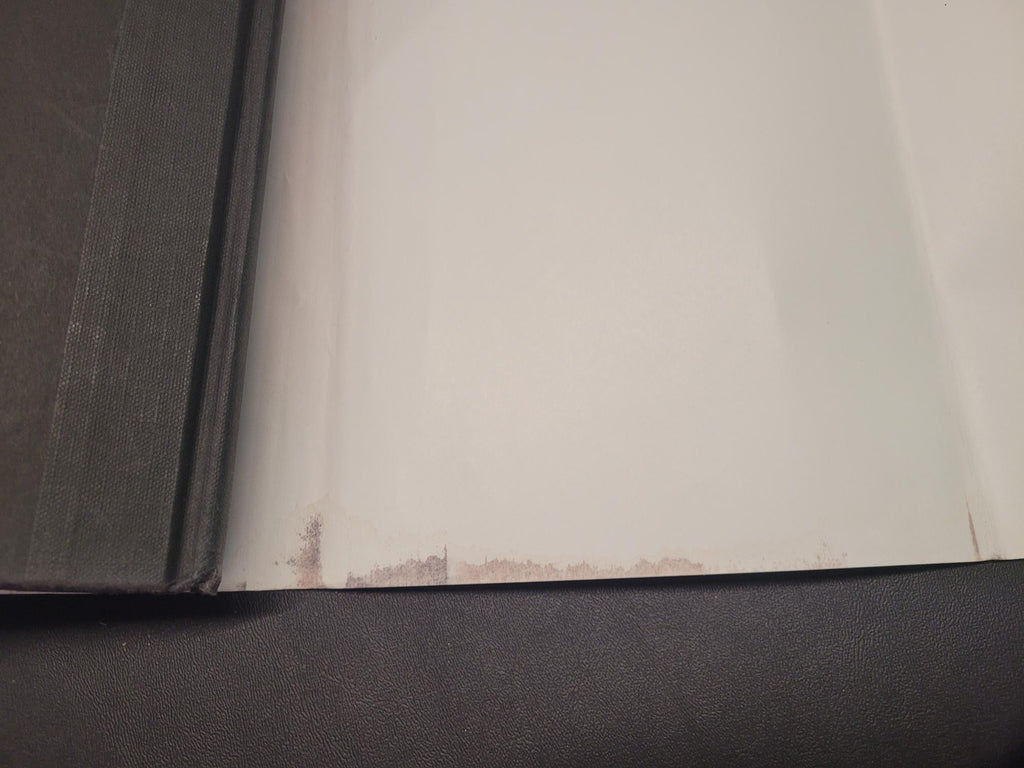 A close-up view of a white surface, likely a screen or panel, showing some scuffs and dirt near the top edge, next to a dark gray textured frame or bezel.