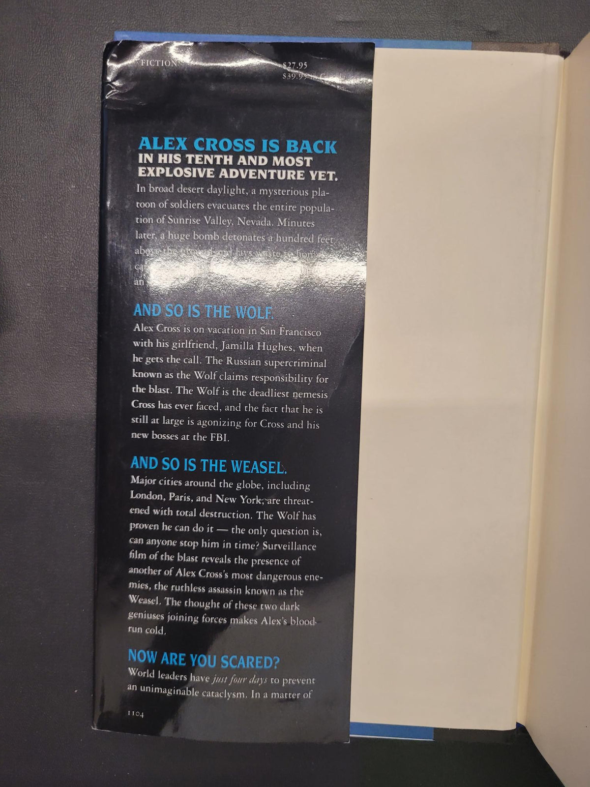 A book or magazine interior spread photographed from above, showing a dark printed page with blue and white text on the left and an off-white page on the right, placed on a dark surface.