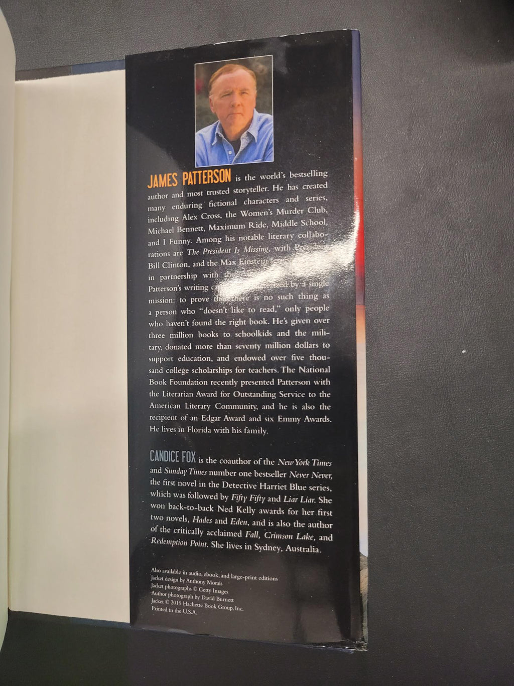 The back cover of a book or booklet, featuring a black background with white text, a small portrait photo of James Patterson, and a white lower section, photographed against a dark surface.