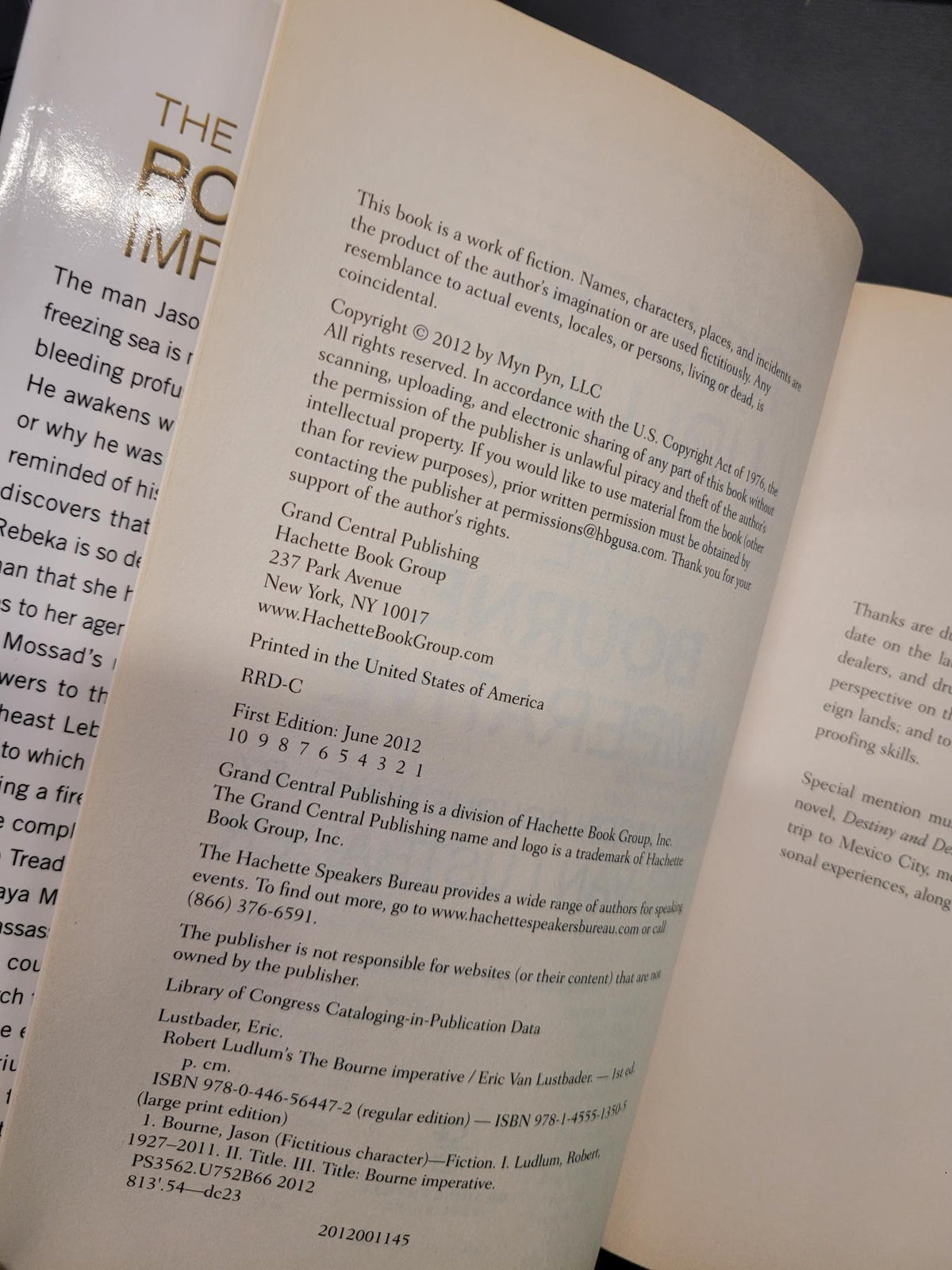 An open book showing printed text and a glossy page reflection, photographed close up against a dark surface.