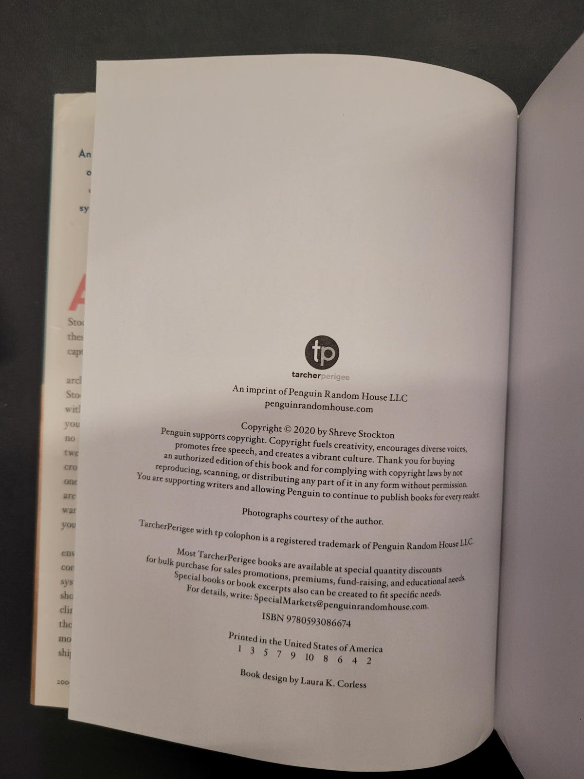 An open book showing the copyright page with printed text and a small circular 'tp' logo, photographed from above on a dark surface.