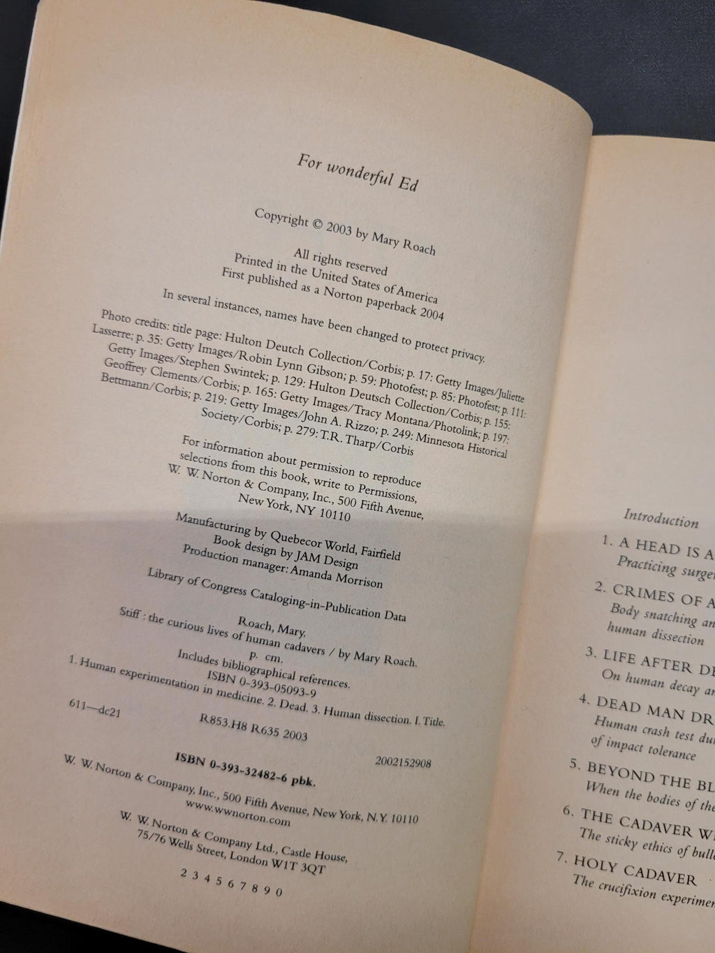 An open book page showing printed text and a table of contents, photographed against a dark blue background.