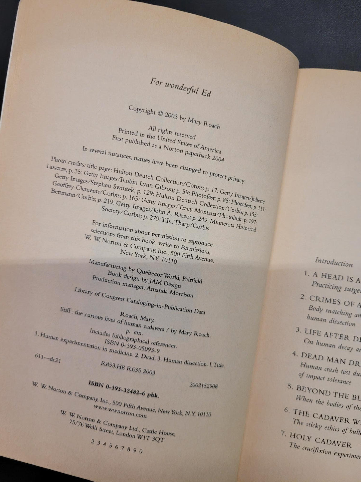 An open book page showing printed text and a table of contents, photographed against a dark blue background.