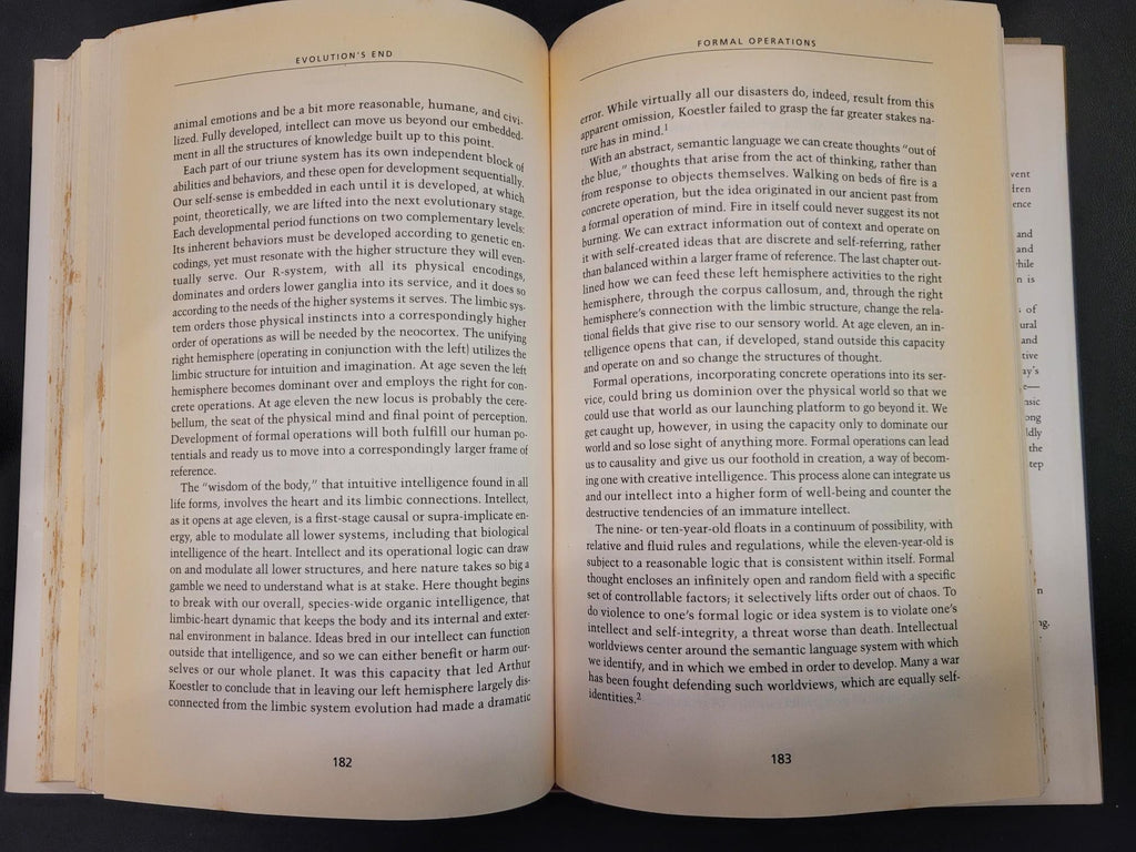 An open vintage book showing two pages of dense black text printed on aged, yellowed cream paper, photographed against a dark background.