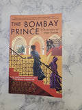 The Bombay Prince (5: Mystery of 1920s of India) book by Sujata Massey, featuring a vintage illustration of figures on a staircase, photographed flat on a white marble surface.