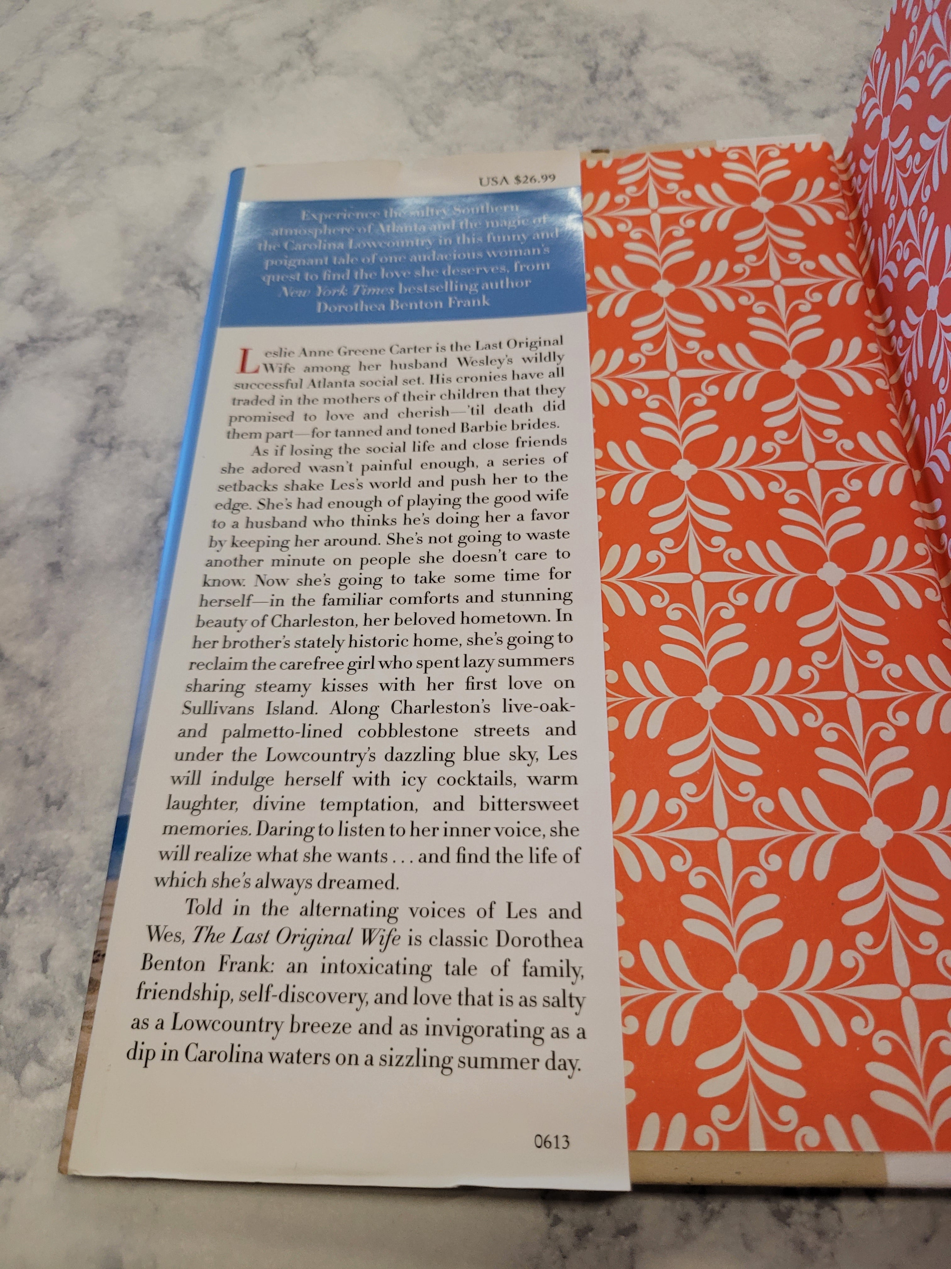 An open book page lying on a marble-like surface, showing printed text and a decorative orange-and-white patterned cover or page edge.
