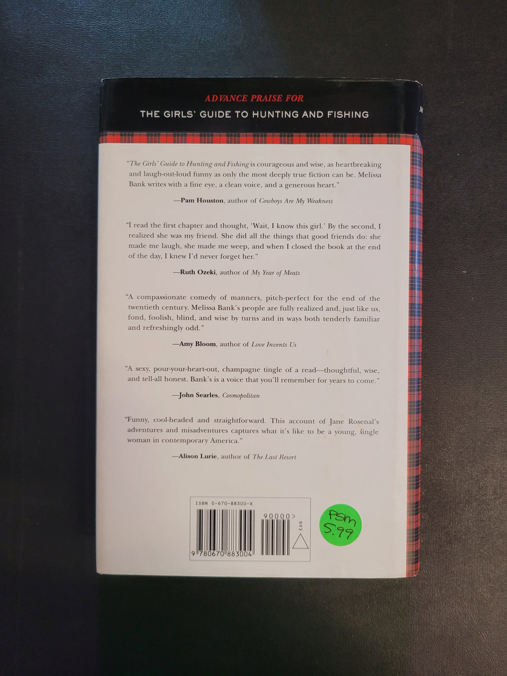 The back cover of a book titled 'The Girls Guide to Hunting and Fishing' by Jeremy Taylor, featuring a white background with black text, a barcode, and a green price sticker, set against a dark textured surface.