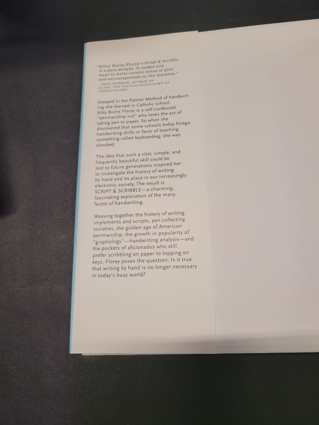 A white folded paper insert with printed black text, photographed on a dark textured surface.