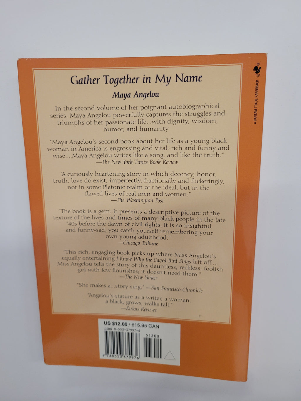 The back cover of the book 'Gather Together in My Name' by Maya Angelou, featuring a solid orange border with a cream-colored central text area and a barcode on the right.