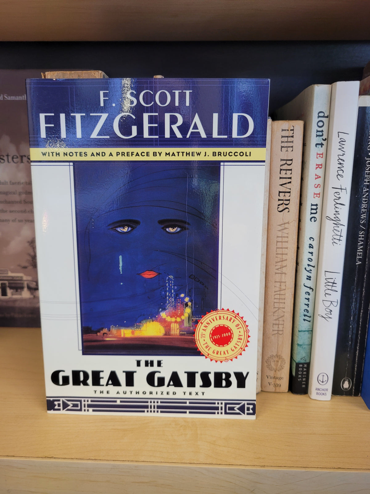 A copy of F. Scott Fitzgerald's 'The Great Gatsby' book standing on a wooden shelf next to other books.