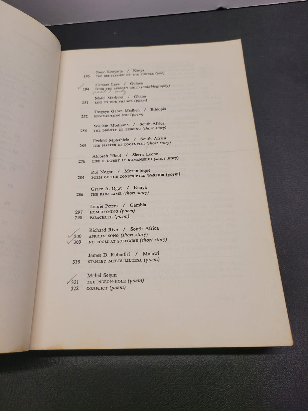 An open book "Black African Voices" showing printed table of contents pages on off-white paper, photographed from above on a dark surface.