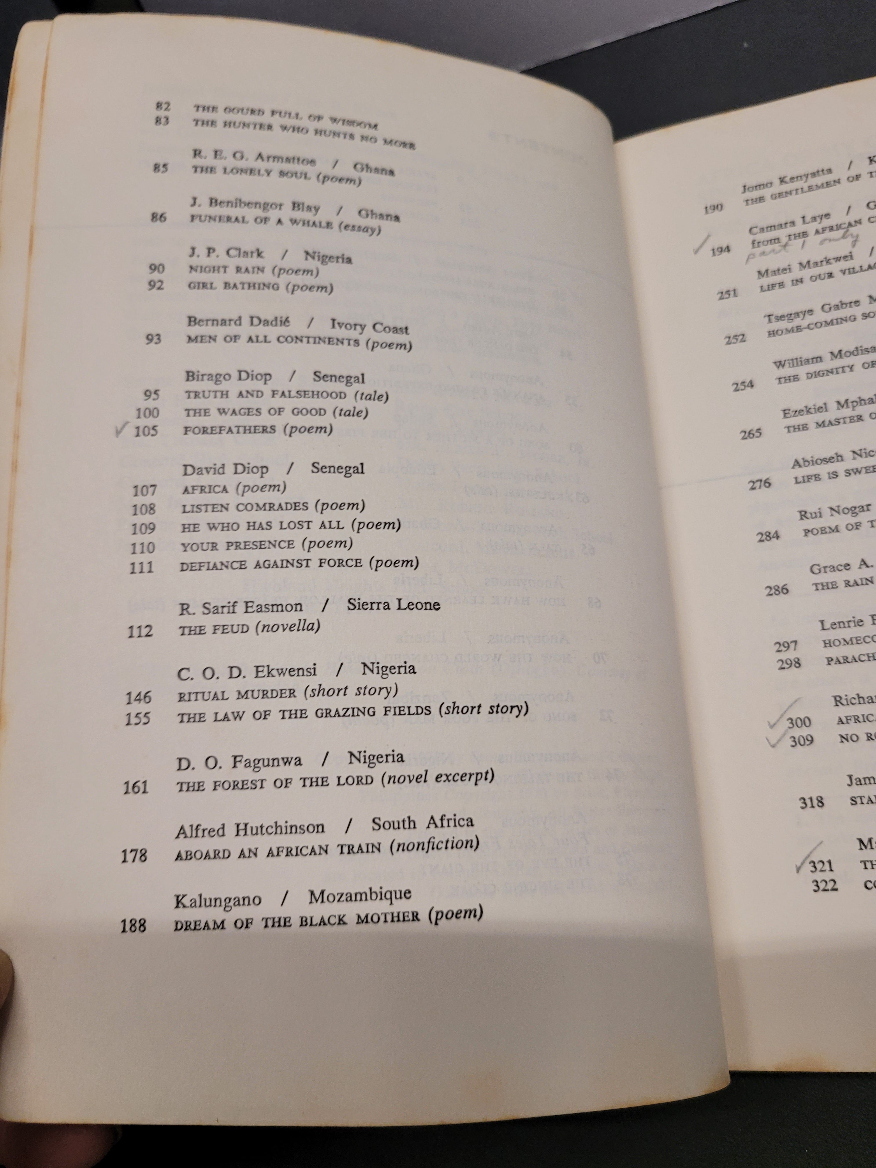 An open book "Black African Voices" showing table of contents pages, photographed from above on a dark surface. The left page has black serif text on off-white paper, and the right page has more text continuing from the previous page.